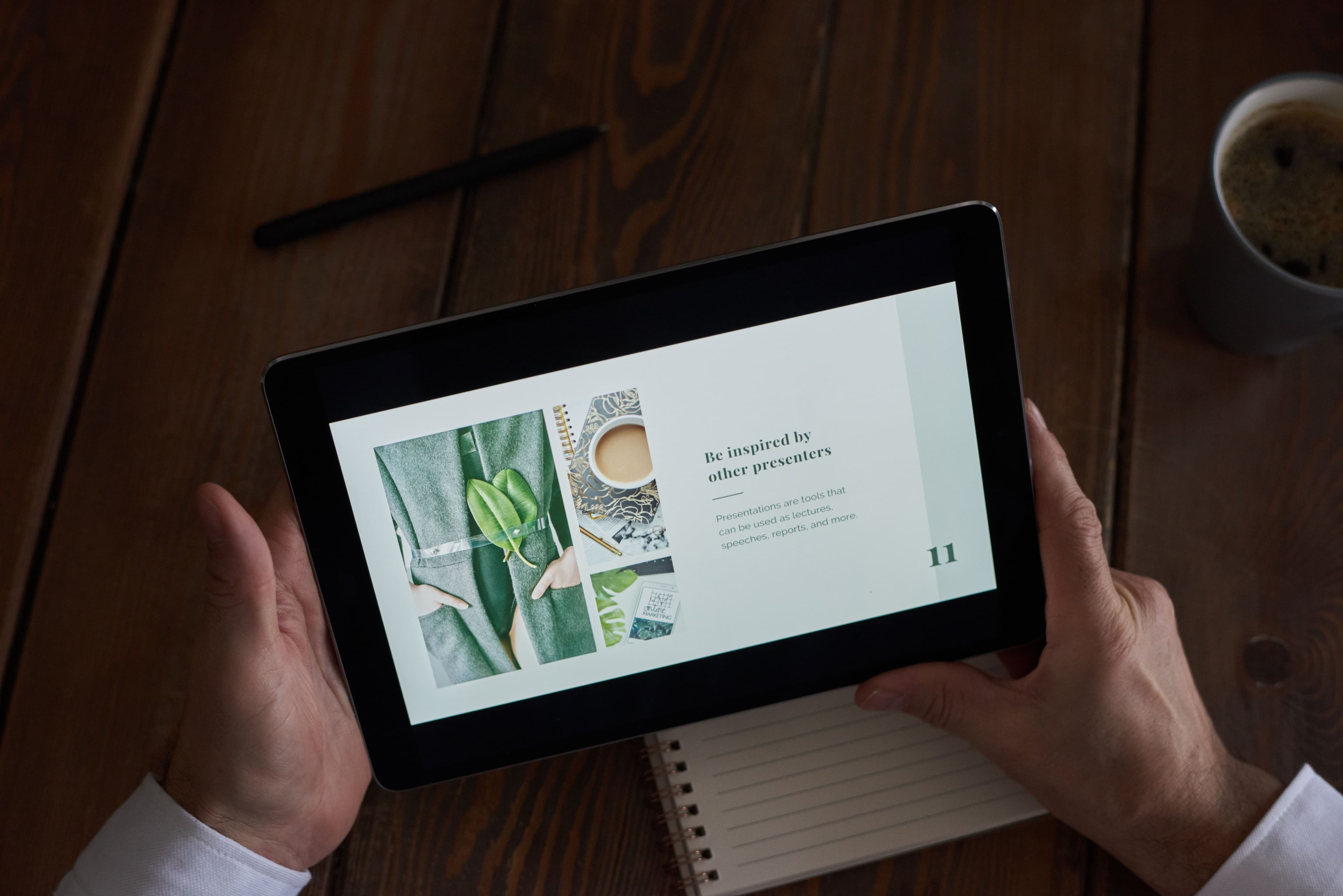 Person holding a tablet with a presentation on a desk.