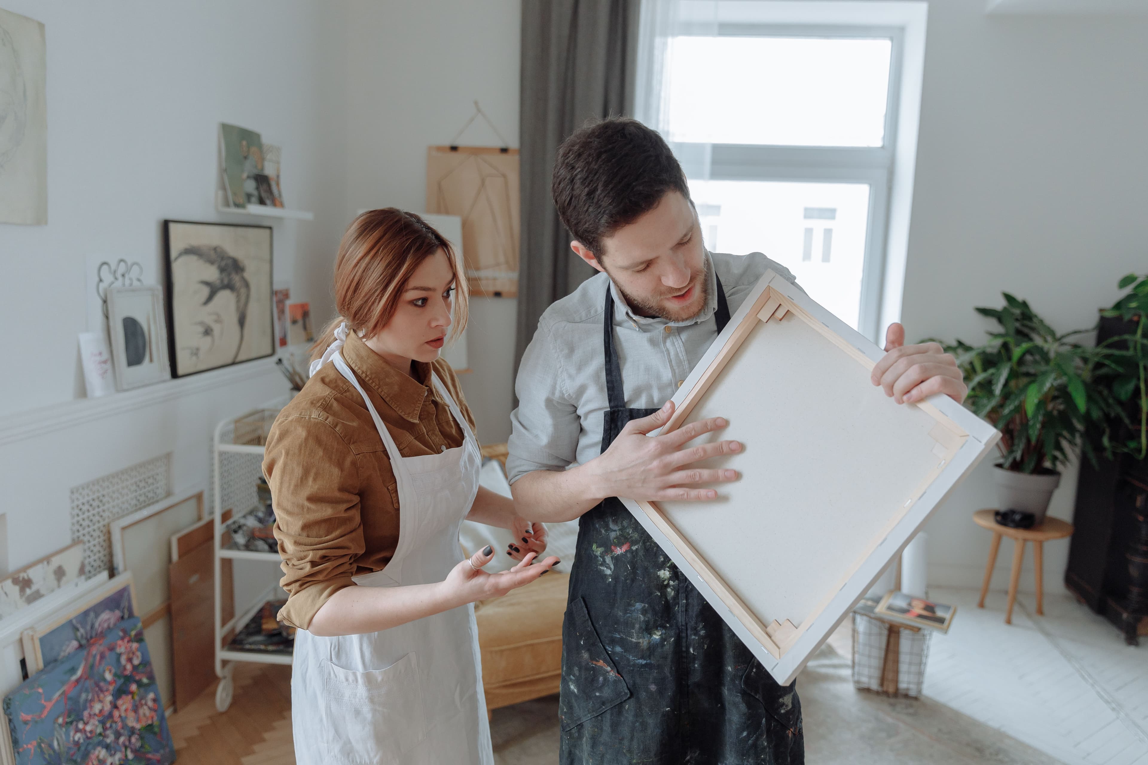Artists discussing a blank canvas in a creative studio.