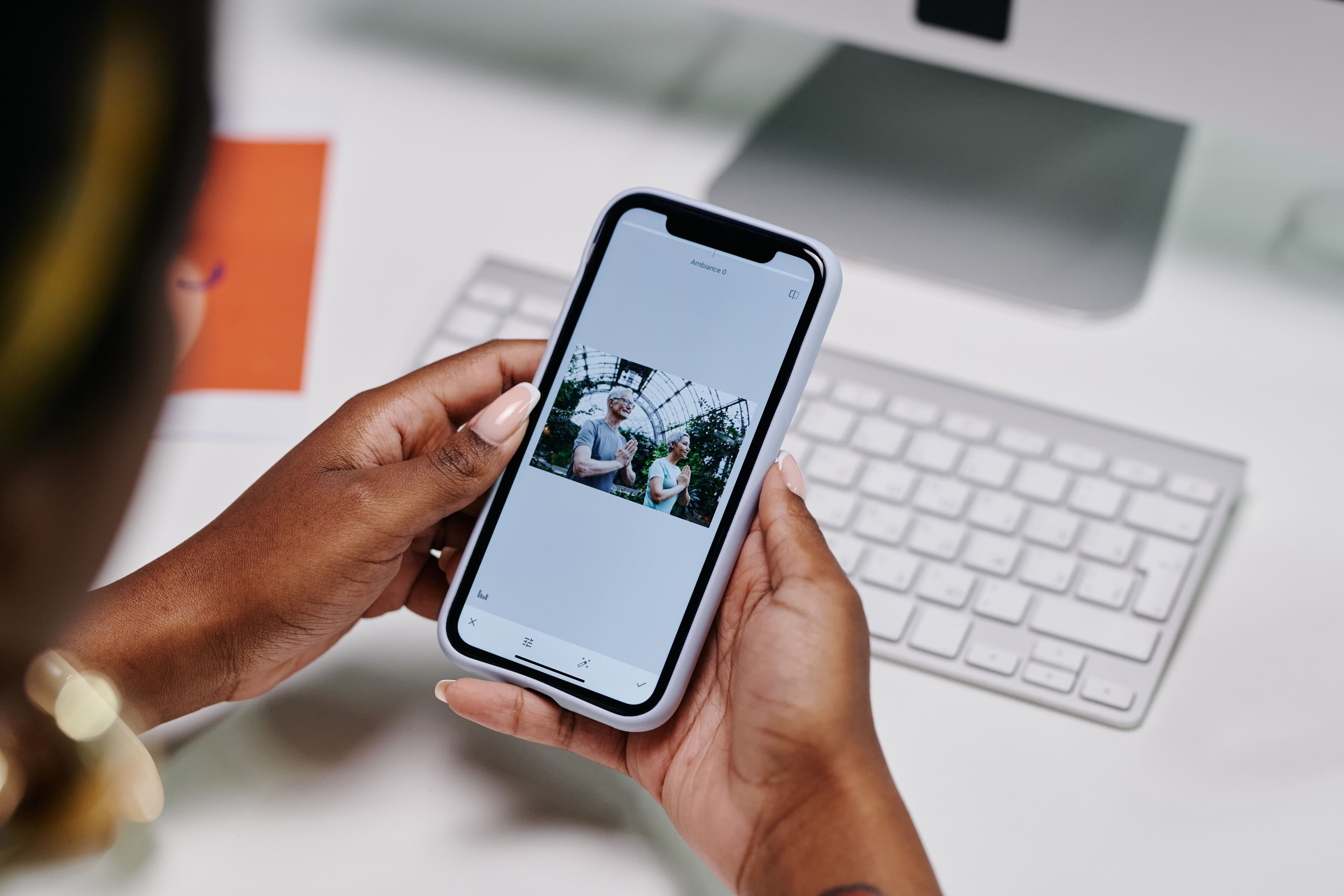 Person viewing photos on a smartphone beside a keyboard.